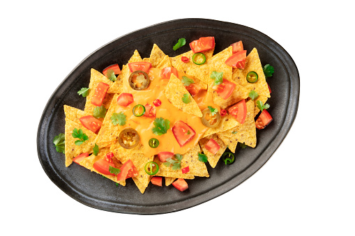 Mexican nachos, isolated with a clipping path. Tortilla chips, shot from the top with a cheese sauce, chili and jalapeno peppers, tomatoes, and cilantro, on a white background