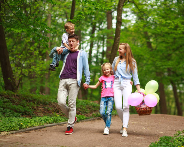 felice giovane famiglia con i loro due figli stanno camminando nel parco forestale estivo, vacanze di genitorialità con i bambini - pensive only baby girls baby girls baby foto e immagini stock