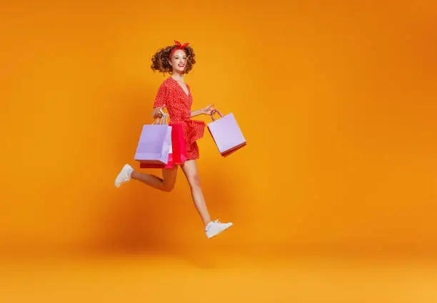 Photo of concept of shopping purchases and sales of happy   girl with packages  on yellow background