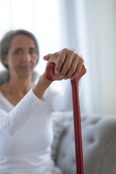 istock Woman sitting on couch while holding a brown walking stick 1161171524