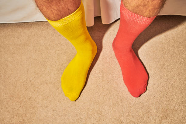 istock mans feet wearing odd socks, coral and yellow. 1161172807
