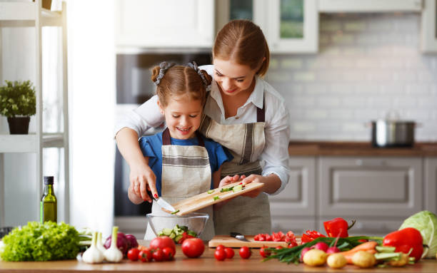 happy family mother with child girl preparing vegetable salad - family mother domestic life food imagens e fotografias de stock