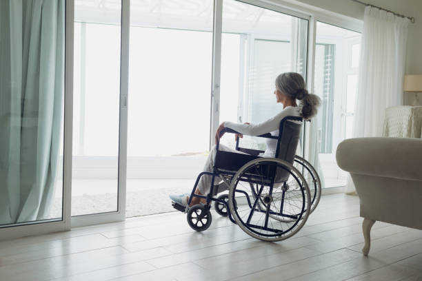 istock Woman on wheelchair looking outside 1161176452