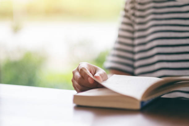 istock a woman holding and reading a vintage novel book 1161176499