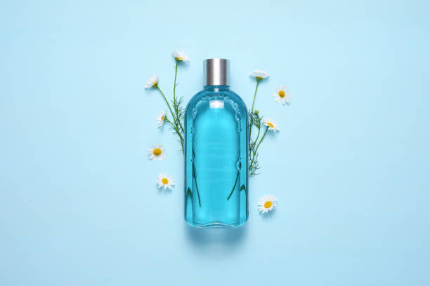Cosmetic bottle and chamomile flowers on blue table top view Cosmetic bottle and chamomile flowers on blue table top view shower gel stock pictures, royalty-free photos & images