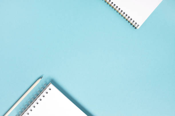 istock Blue background with white open notepads and pencil 1161177768