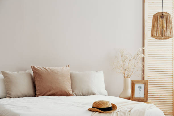 istock Natural fashionable bedroom interior with wicker hat on white bedding 1161177989