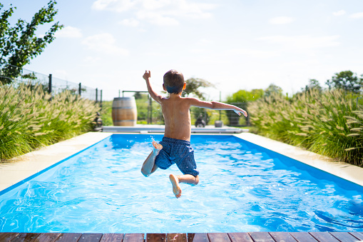 hello summer holidays - boy jumping in swimming pool