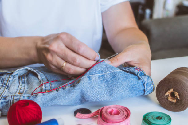 istock women's hands, a tailor sews clothes at a table on which spools of thread lie 1161183681