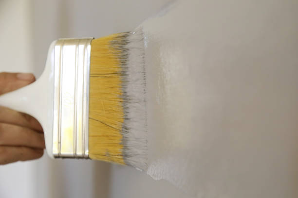 istock Man painting with a paintbrush over a grey wall 1161185532