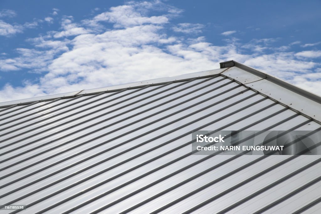 Metal sheet roof and slope with clouds and blue sky background. Rooftop Stock Photo