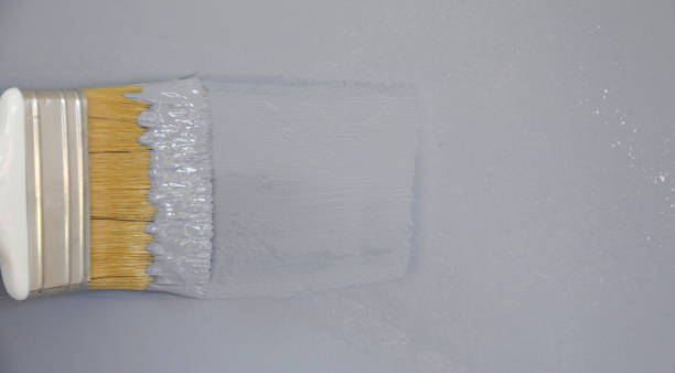 istock Man painting with a paintbrush over a grey wall 1161185832