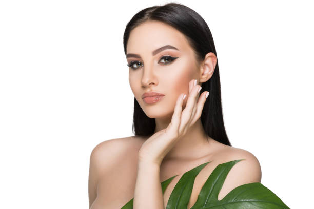 tanned woman face with perfect makeup and healthy skin with tropical leaf isolated on white. cosmetics and face care tanned woman face with perfect makeup and healthy skin with tropical leaf isolated on white. cosmetics and face care gir forest national park stock pictures, royalty-free photos & images