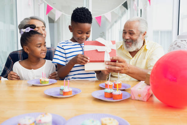 istock Kid opening gift while family watches 1161187770