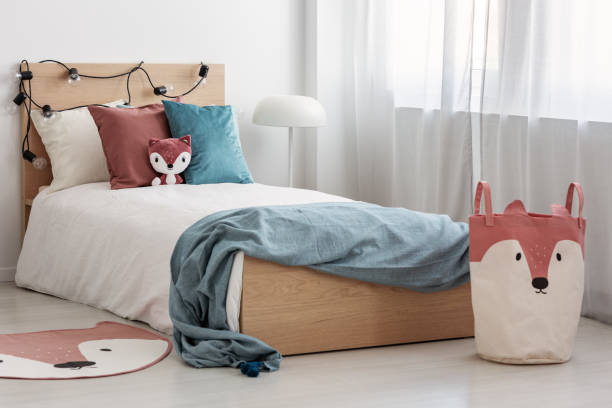 istock Bright bedroom interior with single bed with turquoise blanket on white bedding and colorful pillows and toy 1161187883