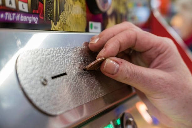 a woman plays a 2p tuppeny nudger machine in a funfair at a british seaside resort. - british currency coin two pence coin british coin imagens e fotografias de stock