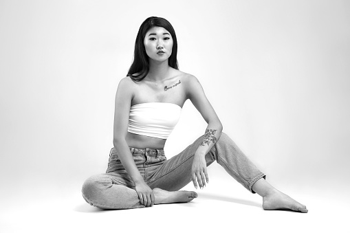 Studio portrait of beautiful young woman wearing white top and blue jeans