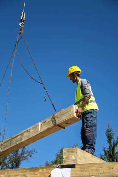 istock Construction worker standing on a wooden house construction site 1161195733
