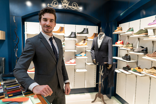Portrait of good-looking  male shoe shop owner in suit, looking at camera