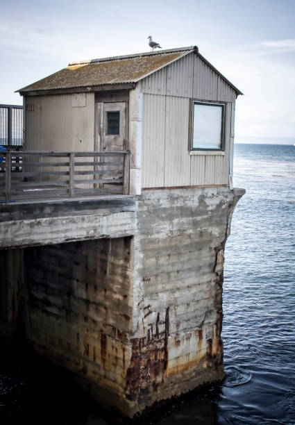 istock Old Abandoned Building on End of Eroding Pier in Ocean 1161200104