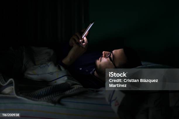 Man Looking His Mobile Phone In The Bed At Night Stock Photo - Download Image Now - Night, Men, Bed - Furniture