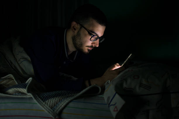 istock Man looking his mobile phone in the bed at night 1161201004