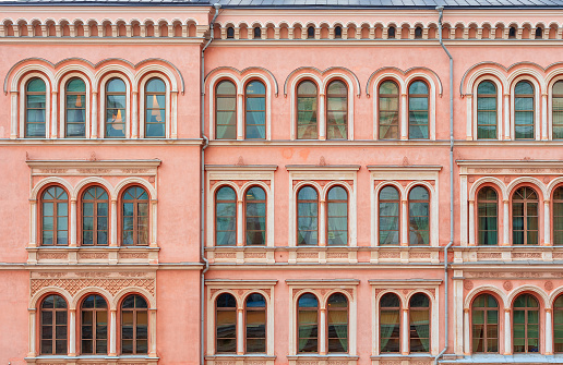 The facade of a beautiful pink city building. Windows with semicircular part