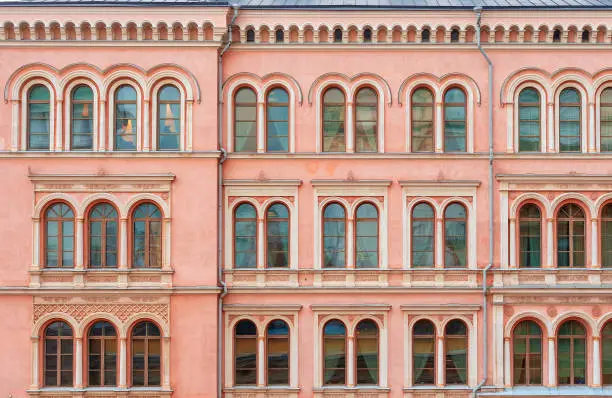 Photo of The facade of a beautiful pink city building. Windows with semicircular part