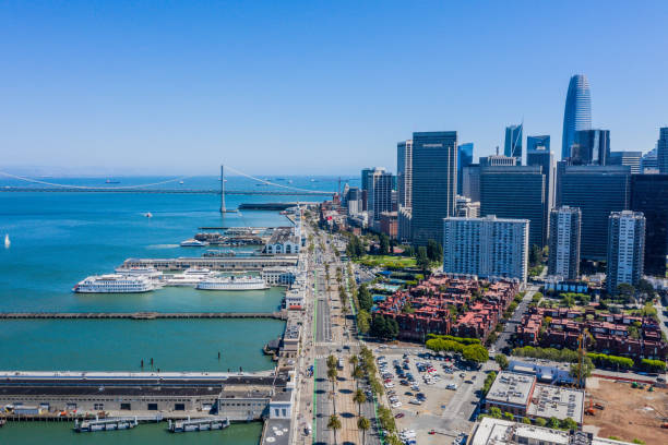 Aerial view of the Embarcadero on a Sunny Day An aerial view ofthe Embarcaderor on a beautiful blue sky day. Ships, ferries and sailboats fill the San Francisco Bay.The iconic Ferry Building and Salesforce Tower surround the famous roadway. san francisco bay stock pictures, royalty-free photos & images