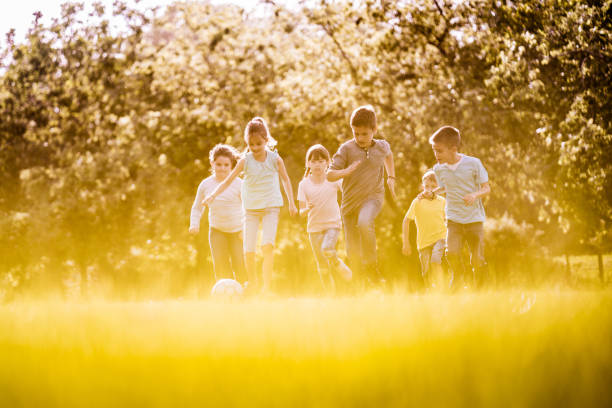 Smiling little girl playing hide and seek and counting while other players hiding, children having fun outdoors on playground