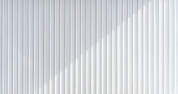Photo of White corrugated metal wall texture with casting shadow. Horizontal background texture.