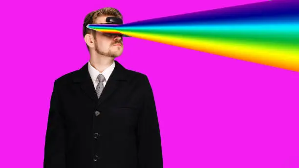 Photo of Businessman in a formal wear wearing virtual reality glasses projecting rainbow rays from the eyes
