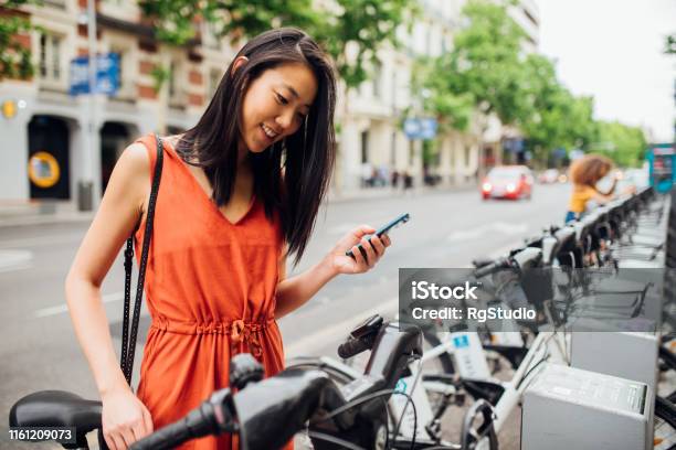 Young Woman Taking Bicycle Stock Photo - Download Image Now - Bicycle Sharing System, Cycling, Electric Bicycle