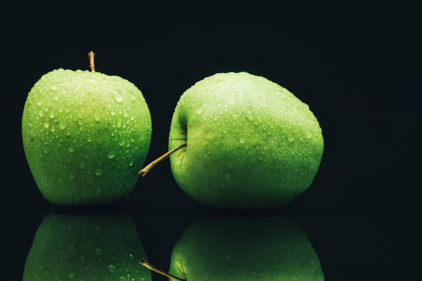 istock Two green apples on a black glass table background. 1161210251