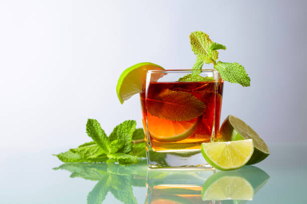 Cocktail with lime and mint on a glass table. Cocktail or cold tea on a white background. Copy space.