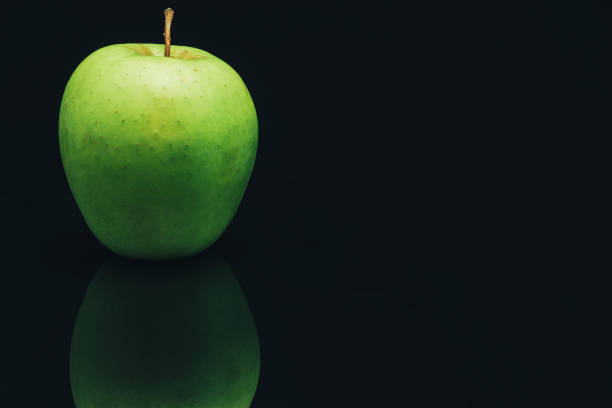istock Green apple on a black glass table background. 1161218980