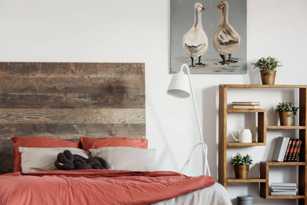 istock Comfortable king size bed with wooden rustic headboard and white industrial lamp next to it 1161219059