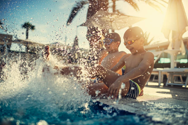 bambini che si divertono a sguazzare in piscina - cheerful swimming pool happiness resort swimming pool foto e immagini stock
