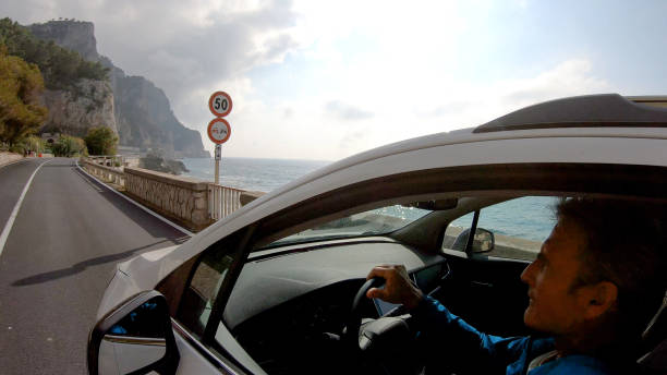 Mature man drives car along the seaside