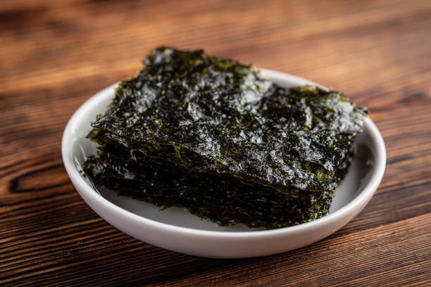 korean roasted seaweed on wooden background korean roasted seaweed on wooden background nori stock pictures, royalty-free photos & images