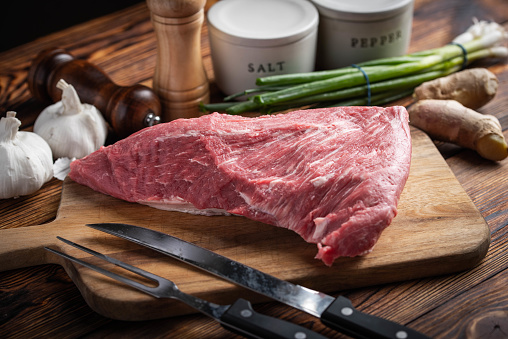 raw tri tip steak beef on wooden cutting board