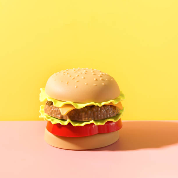 istock Plastic burger, salad, tomato with on yellow. 1161221025