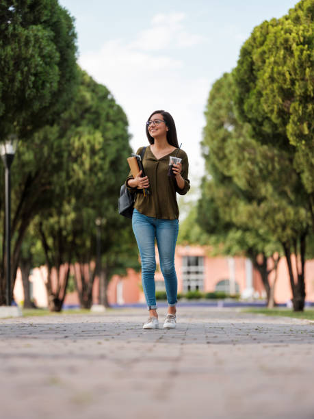 college girl walking with a soda cup - adult education full length book imagens e fotografias de stock