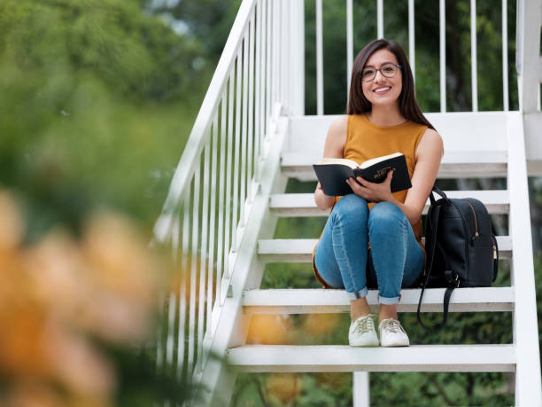 istock Smiling university student holding an open Bible and looking at the camera 1161222749
