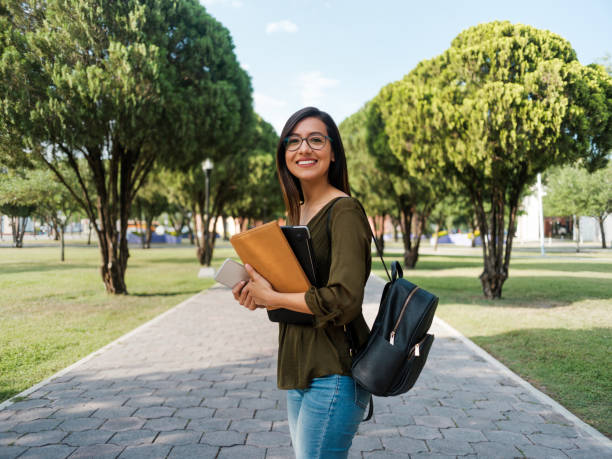 latina college-mädchen, das mit einem lächeln in die kamera schaut - universitätsstudent stock-fotos und bilder
