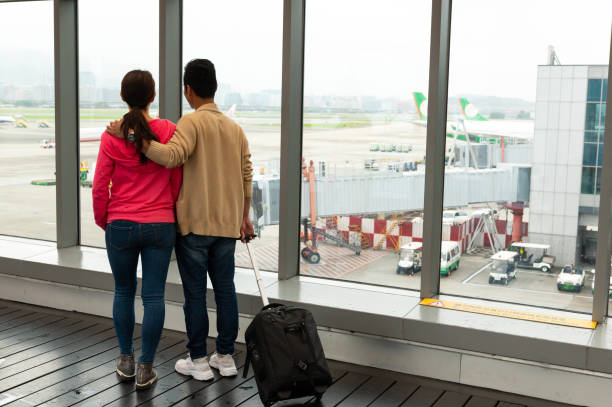 istock Couple looking through window at airport 1161222842