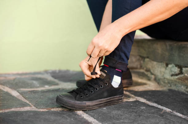 Cropped shot of young woman wearing shoe outdoors