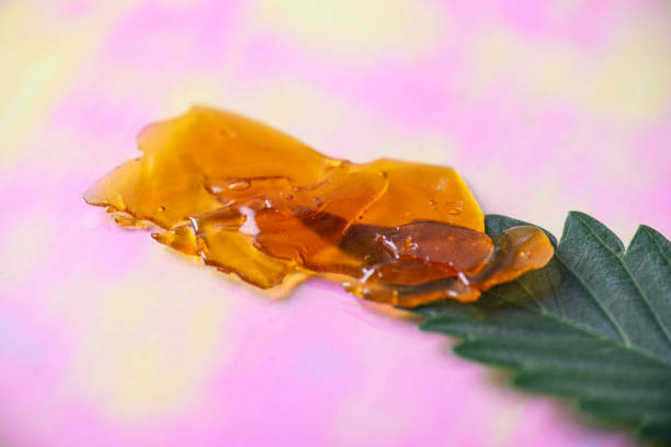 Dab tool with cannabis concentrate aka shatter and marijuana leaf, stock photo