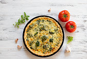 Traditional French Quiche with cheese, broccoli, spinach and chicken. Quiche lorraine. French cuisine. Top view. Light wooden background