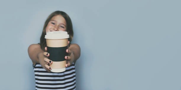 Smiling girl giving, showing coffeecup closeup side view